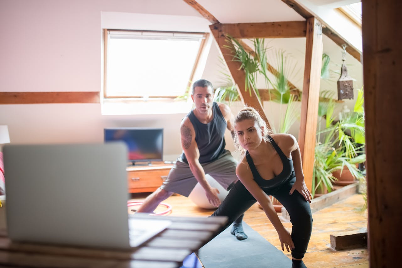 About A man and woman working out at home using a laptop for guided exercises. Indoor active lifestyle.