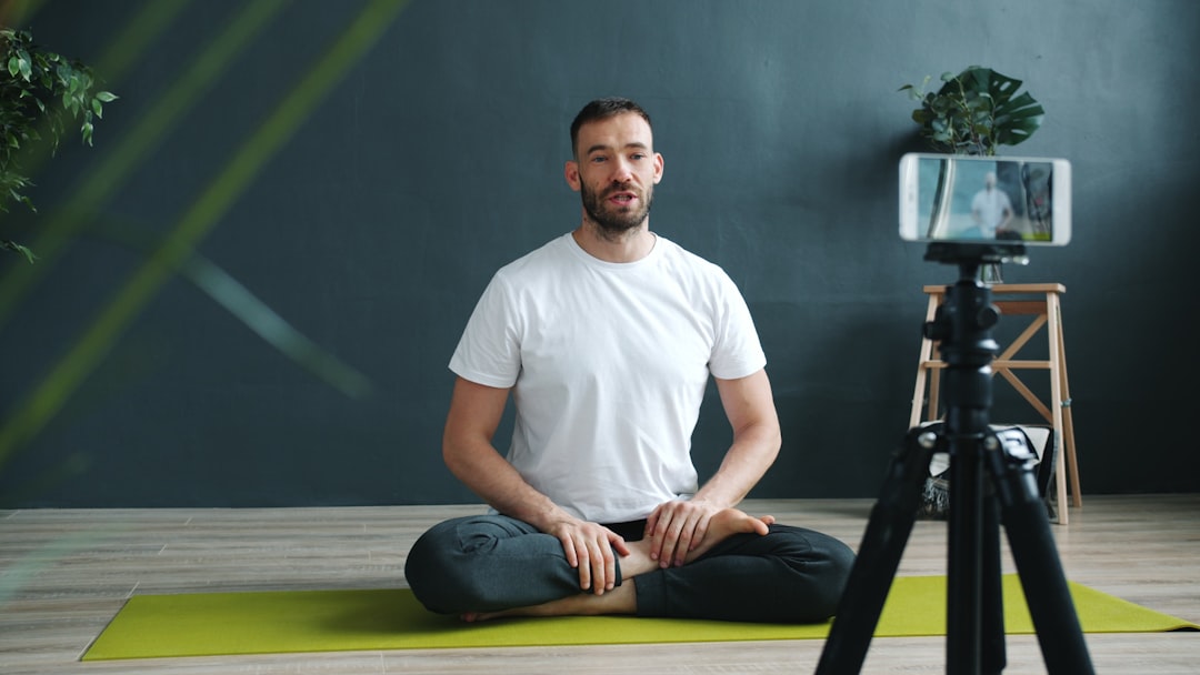 Home Handsome man vlogger recording video tutorial in yoga studio doing asanas using smartphone camera creating content for internet vlog. People and vlogging concept.